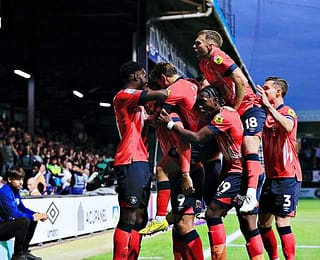 Carlton Morris is mobbed after scoring against Sheffield United this evening